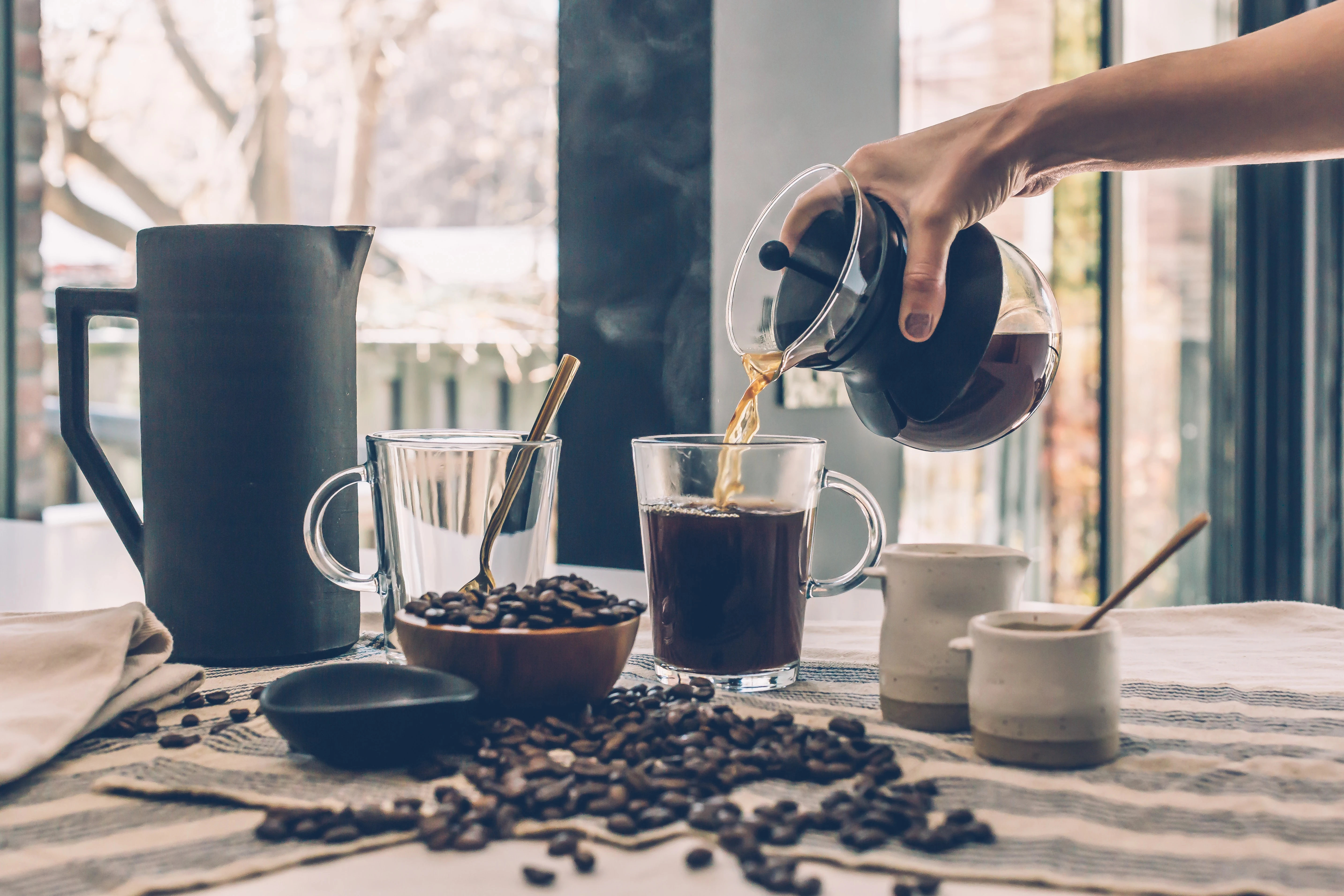 Person filling clear glass mug with coffee