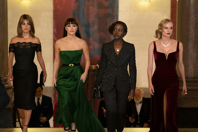 Four women in formalwear enter a room at the same time