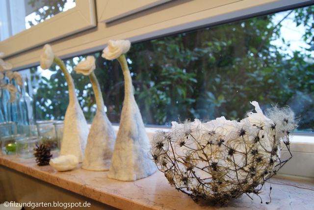 Clematis-Schale und weiße Filzblumen auf der Fensterbank
