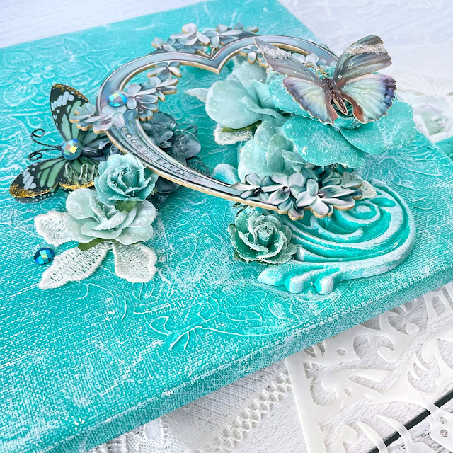 Mixed media canvas created with: Prima Marketing lace paper flowers, coffee break, Zella teal, magical love, finnabair jade impasto paint, grungy succulents, bindweed stencil; Reneabouquets patina lilac chipboard heart frame, into the mystic butterflies, gawdie girl glitter glass in ocean