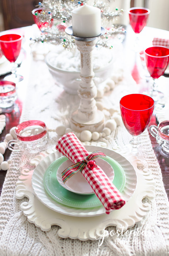 red gingham napkin on green and white dishes for a Christmas table setting
