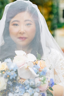 bride with veil covering her face holding flowers looking at camera