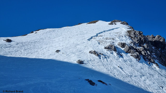 Eine Person fuhr am 13.03. orographisch links in den Hang ein. Man erkennt dort einen schneeärmeren Bereich. Die Person wurde von dem Schneebrett mitgerissen und wurde leicht verletzt. Schafkar, 2300m, SO, 35-40°.