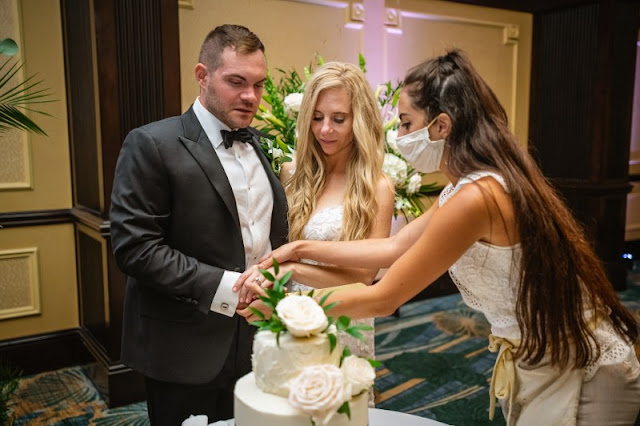 at last weddings coordinator showing couple how to cut cake