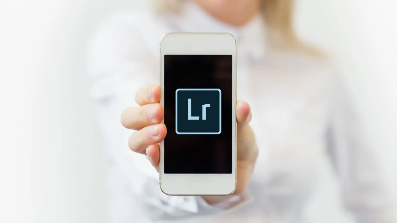 Woman holding mobile phone with Adobe Lightroom logo on it.
