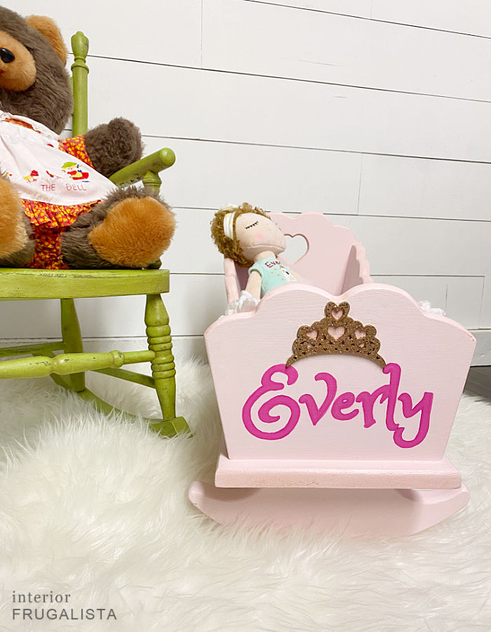 A vintage wooden doll cradle makeover painted a pretty pink and personalized with hand-painted child's name and DIY bedding fit for a little princess.