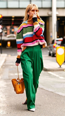 a lady in multi colored sweater and green pants