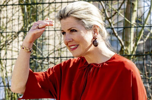 Queen Maxima wore a red silk blouse and red wide-leg trousers. Gianvito Rossi red pumps and Monies earrings. Dutch Council for Refugees