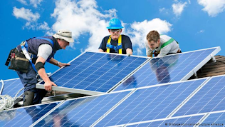 three men installing solar panel on roof