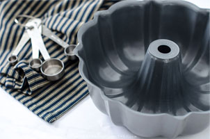 Bundt pan and measuring spoons on blue dish towel