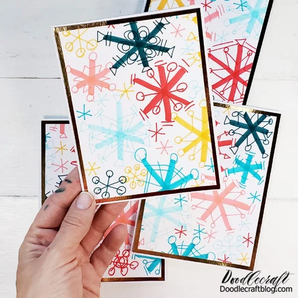Cut the gold cardstock 1/8" larger than the snowflake paper and mount them together. Then cut 2 pieces of cardstock in half and then fold them in half to make the perfect cards. Adhere the gold/snowflake layered card on top of the folded card, leaving a small border again.