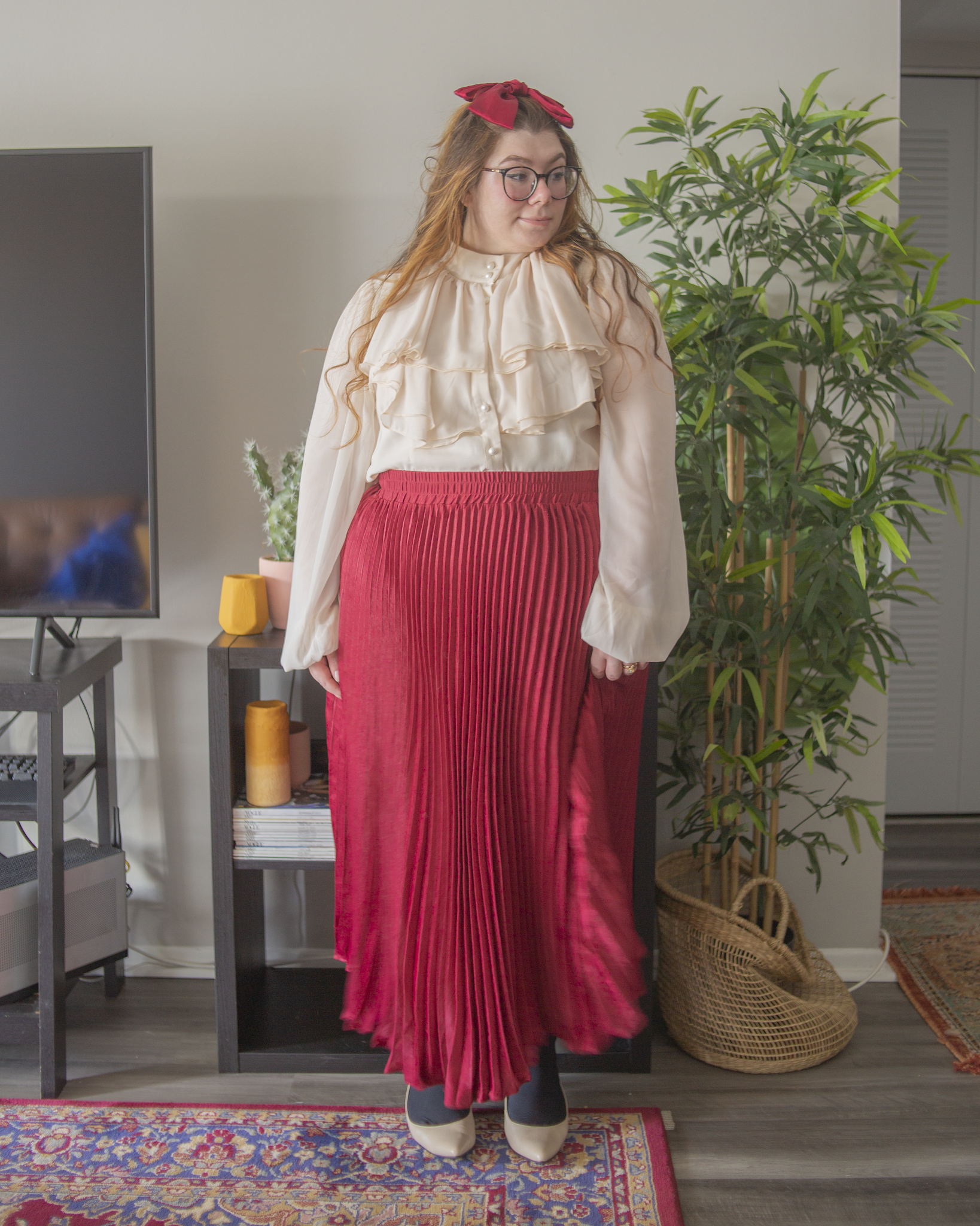 An outfit consisting of a white high neck sheer bishop sleeve blouse with Edwardian inspired neck ruffles tucked into a wine red pleated maxi skirt, with black tights and cream slingback heels.