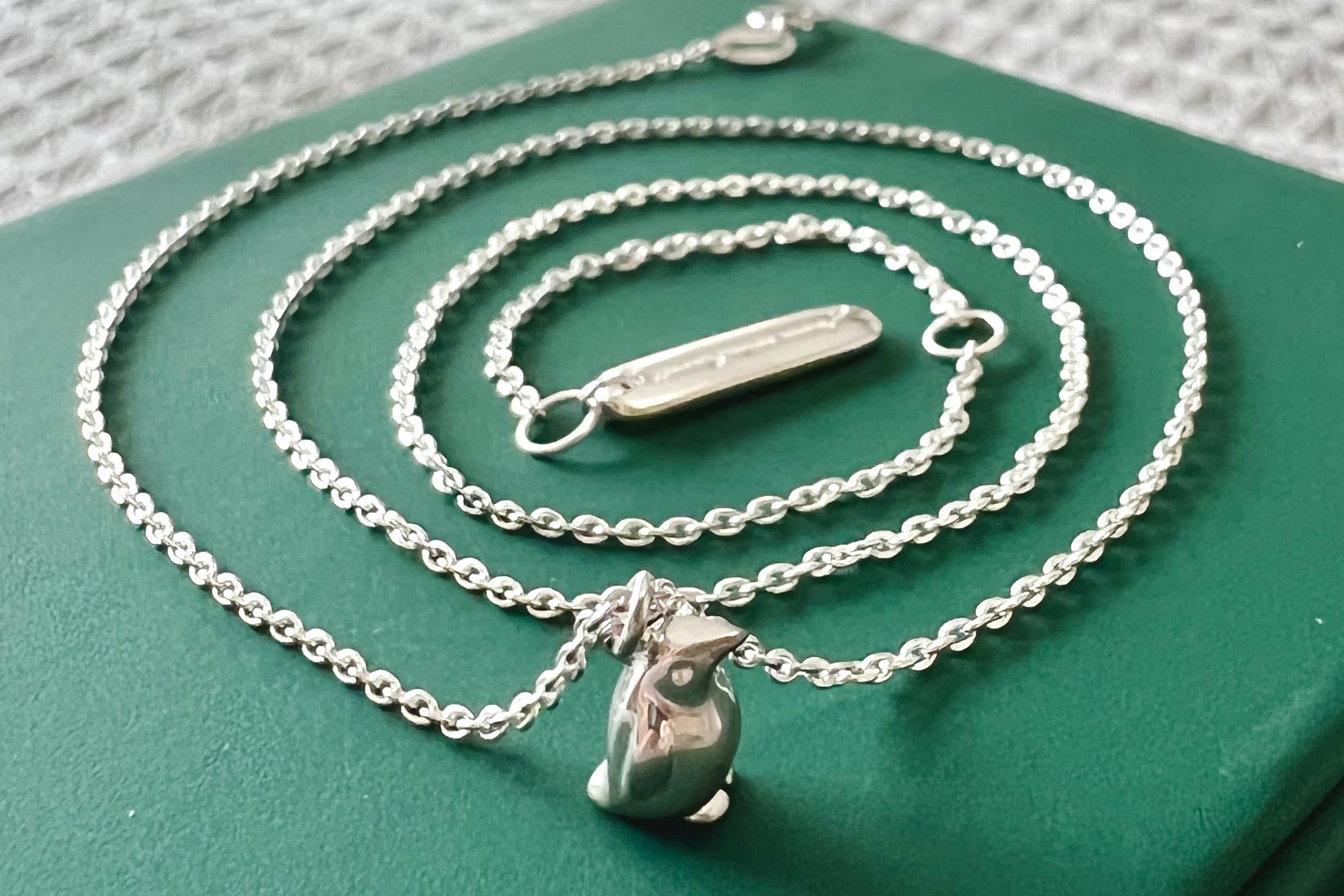An adjustable length silver necklace with a tiny penguin pendant