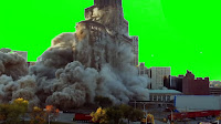 A builkding collapsing in a large cloud of dust and debris all set against a green background.