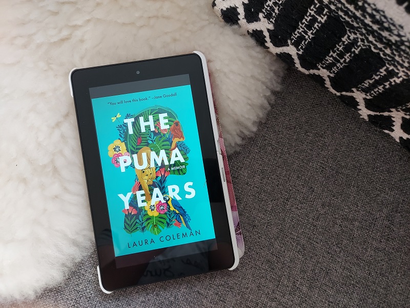 The Puma Years - Kindle screen with jungle themed book cover open, against a sheepskin throw on grey fabric sofa