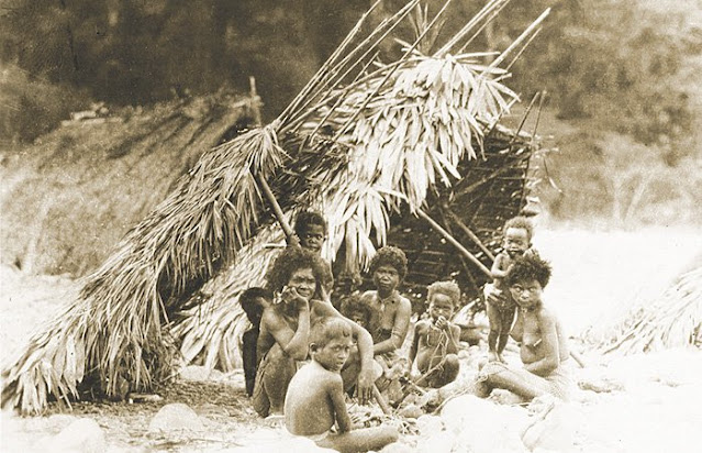Aeta family in their traditional lean-to house made of nipa leaves