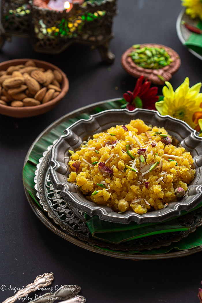 Moong dal halwa served in metal bowl garnished with slivered nuts