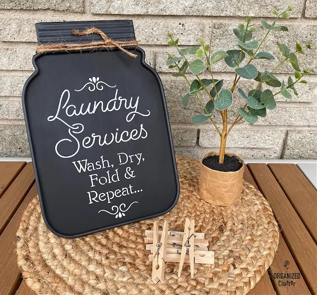 Photo of a jar shaped metal chalkboard with easel repurposed into a fun farmhouse laundry room sign.