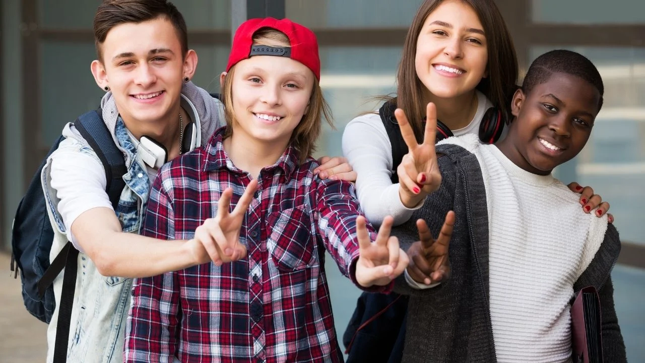 Portrait of four smiling teenage students close to university.