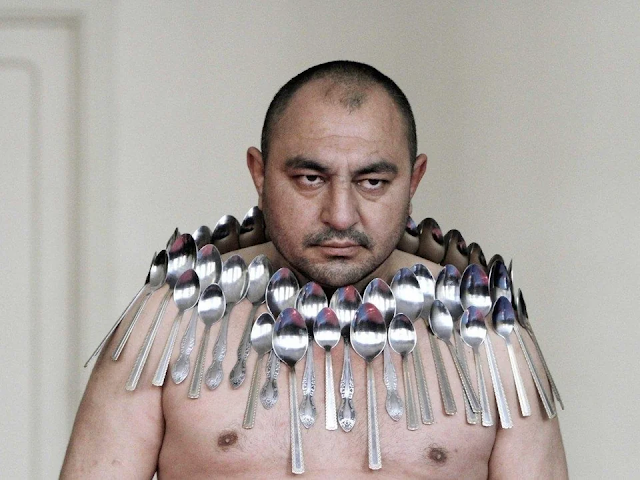 A man with spoons stuck all over his body.