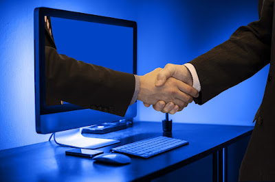 Photo of a handshake through a computer screen