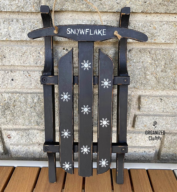 Photo of a small sled painted black with snowflake stenciling.