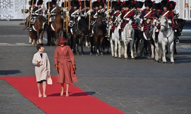 Queen Mathilde wore a dusky pink wool coat by Natan, and pink silk top and pleated skirt by Natan. Doris Schmidauer wore a blue dress