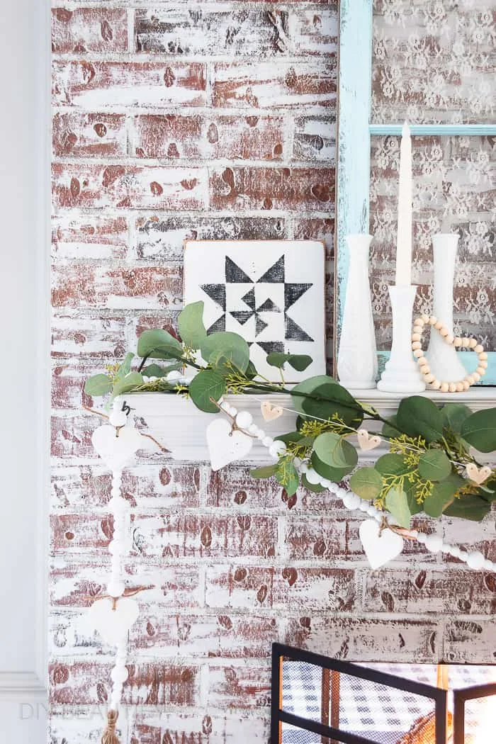 milk glass, barn quilt, greenery, garland, white hearts on painted fireplace mantel