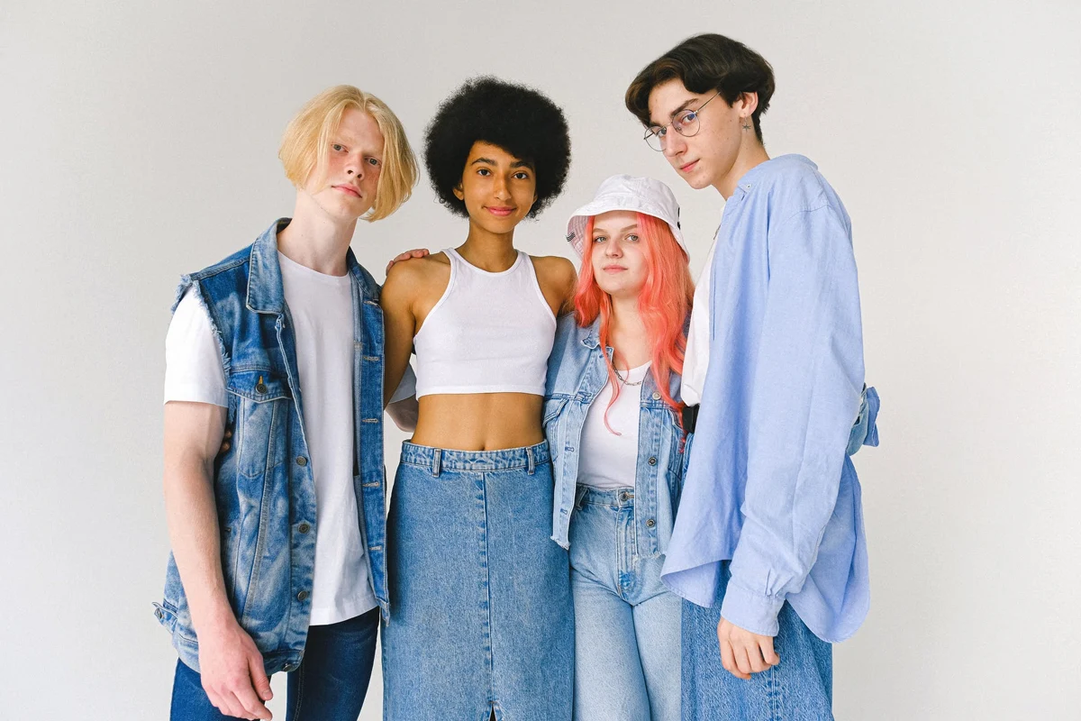 four people wearing simple unisex outfits posing in a studio