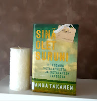 Kirja seinähyllyllä valkoisen kynttilän vieressä