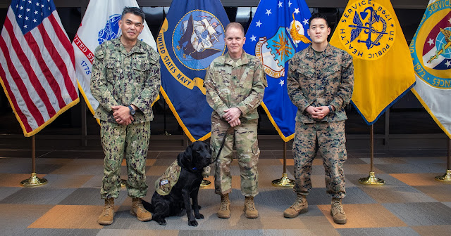 USU’s newest facility dog, Sgt. Grover (center), is surrounded by his command leadership, Senior Enlisted Leader Navy Master Chief Michael Jimenez, Army Col. Patrick Donahue, Brigade Commander; and Marine Corps Capt. Thomas Kim, Headquarters Company Commander.  (Photo by MC3 Brooks Smith)