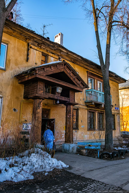 Двухэтажное здание с массивным деревянным козырьком над подъездом