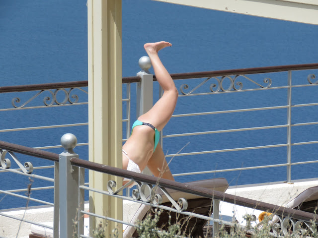 Against the backdrop of the sea, a young girl shows off her fit body while  Exercising