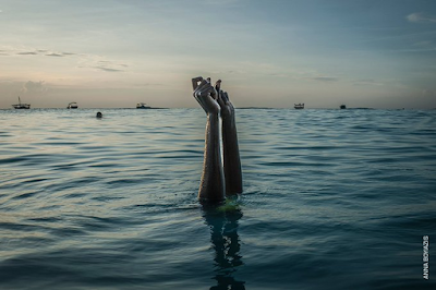 color photograph of arms outstretched above water of a swim instructor in Xanzibar