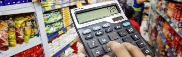 pessoa com uma calculadora na hora de fazer compras no supermercado