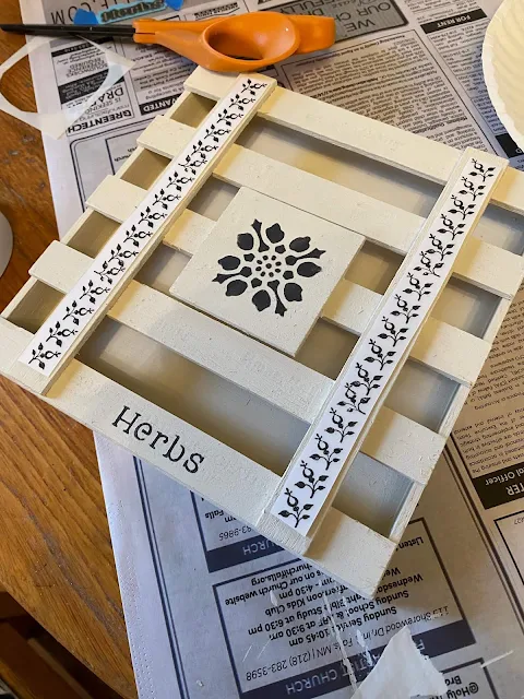 Photo of a small painted wooden box being decorated with stencils & rub on transfers.