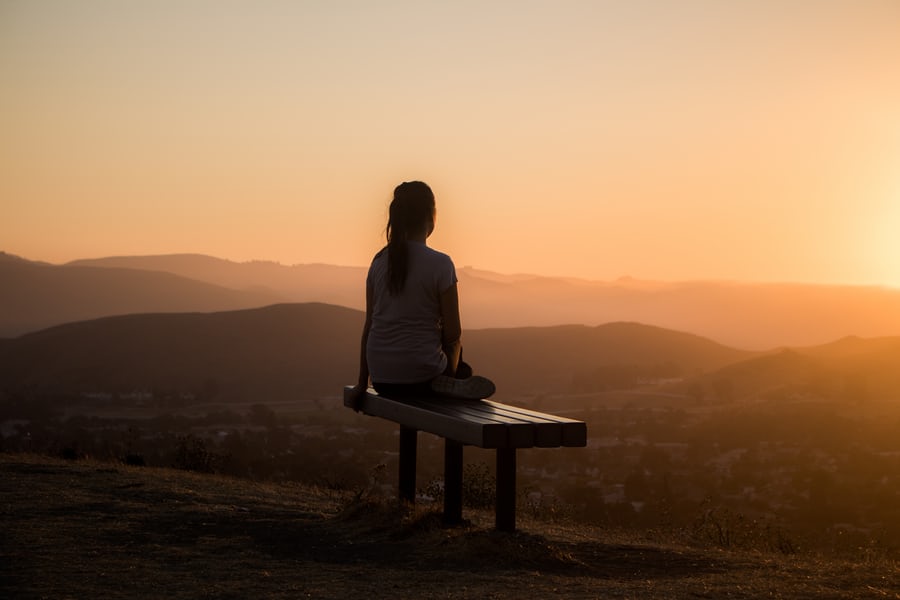 A woman sitting on a bench , meditating to lose weight