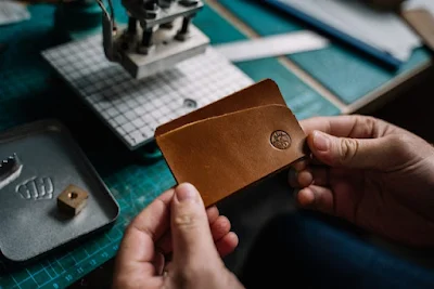 A Person Holding Brown Leather Wallet With Embossed Brand Symbol
