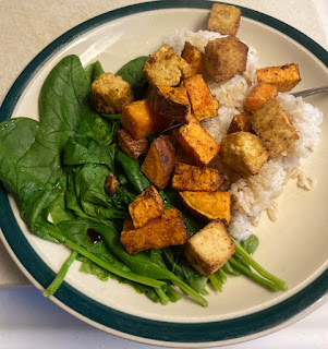 A plate showing spinach, rice, fried tofu and sweet potato chunks.