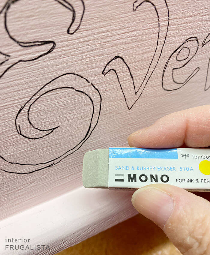 How to erase carbon paper markings from traced typography on a painted wooden cradle with an eraser with grit.