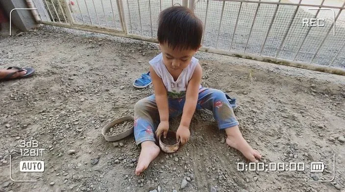 A little boy sitting on the ground while playing in the dirt