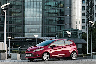 Une Ford avec un grand immeuble vitré en arrière-plan