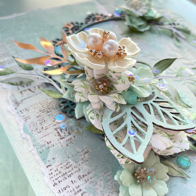 Mixed media canvas made with: Prima watercolor floral paper, paper flowers, gems, chipboard, Finnabair impasto paint, metallic flakes copper, indigo metal charms; Tim Holtz salvaged patina glaze and paint; Picket Fence iridescent moonshine sequins