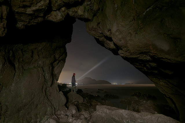 cueva en la playa de Berria con un haz de luz de linterna