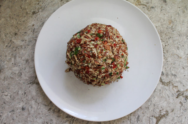 Pile any leftover pecan/veggie bits in the middle of your serving plate and, using your hands, pop the cheese ball on top, pressing down gently.