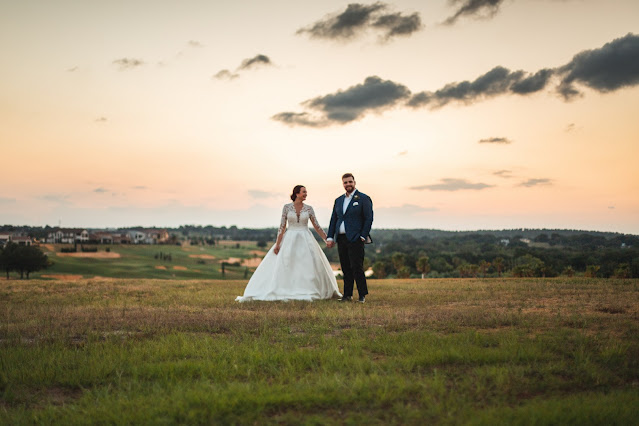 bride and groom holding hands with cloudy sky