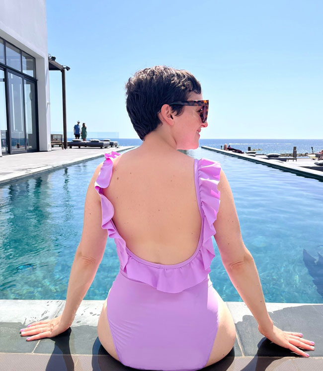 Back view of Tilly wearing lilac swimsuit with ruffle neckline