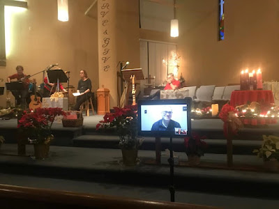 A tablet on a tripod of an interpreter near the lectern with a band singing in the background.