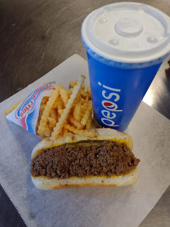 a loosemeat sandwich of ground beef and pickle slices fill a hot dog bun, next to a single serve paper bag of crinkle fries, and a large paper cup marked Pepsi, from Billy Boy in Sioux City