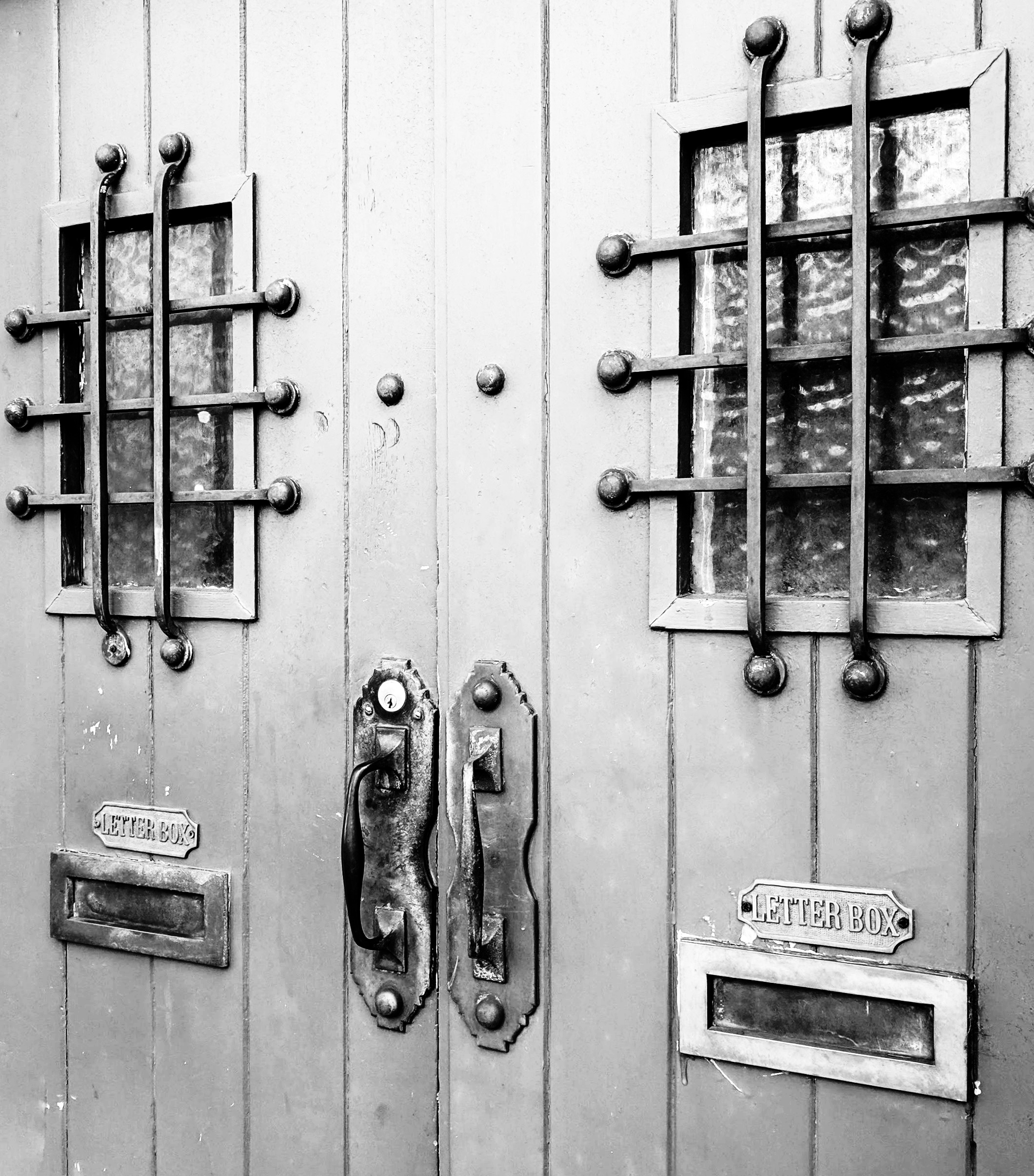 Black and white photo of prison like doors with letter boxes